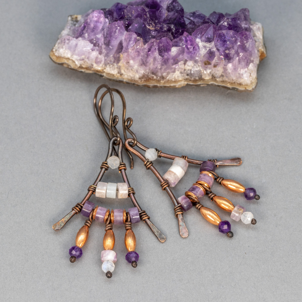 Earrings with white and purple stones wired to a triangular copper frame