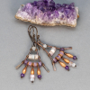 Earrings with white and purple stones wired to a triangular copper frame