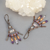 Earrings with white and purple stones wired to a triangular copper frame
