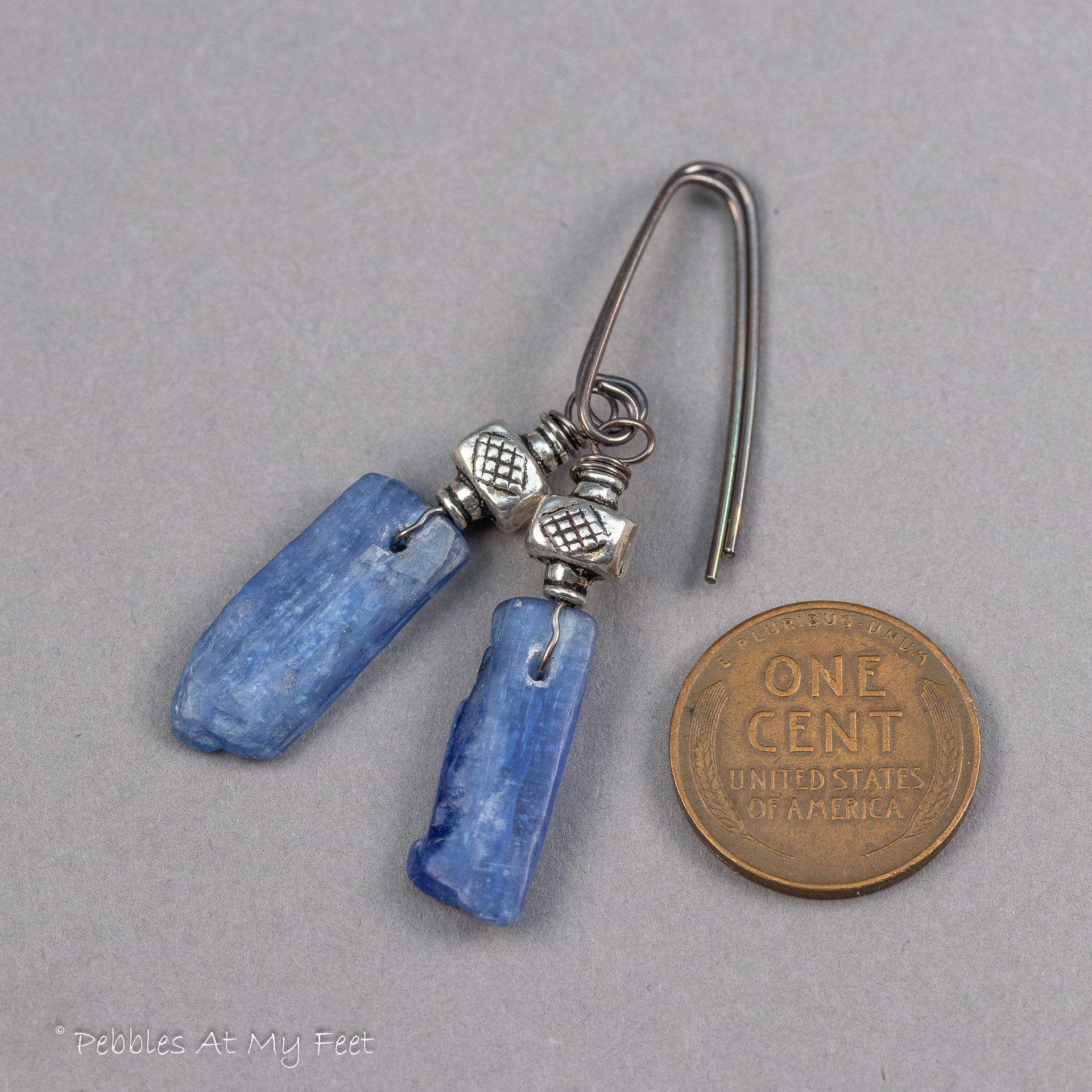 Denim blue stone earrings measure 2 inches long. Shown with a penny coin for scale.